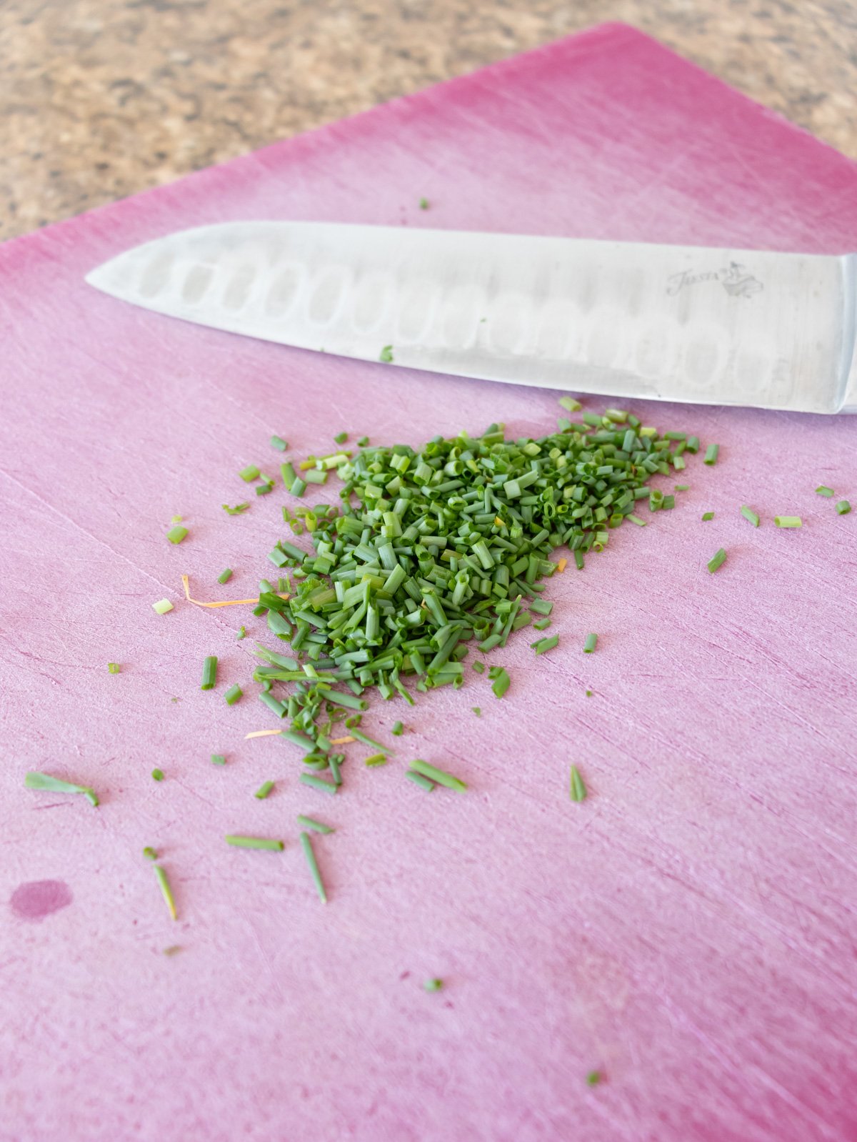 Mincing chives on a cutting board.