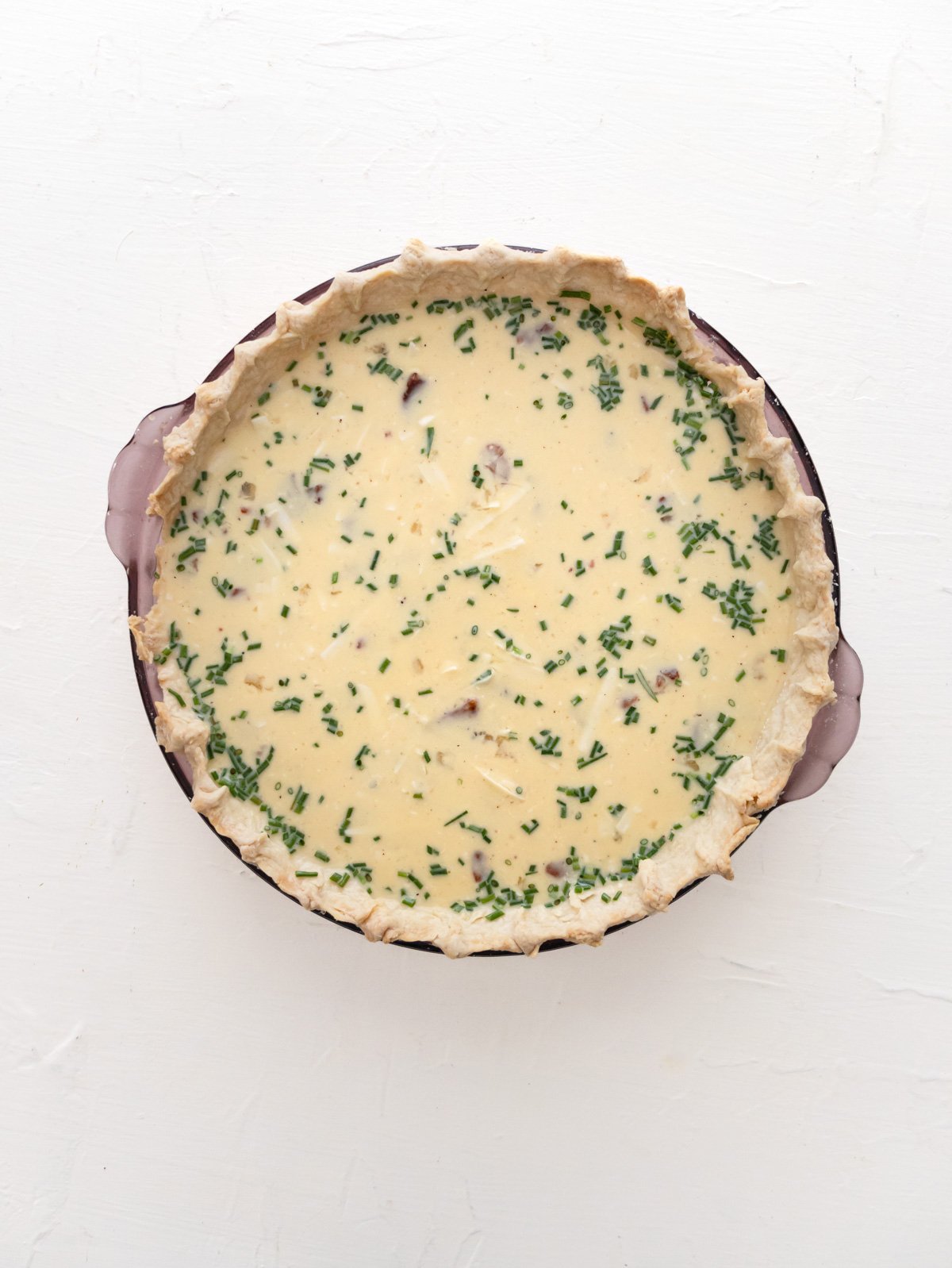 Crispy Bacon Onion Gruyere filling inside a pie crust getting ready to go in the oven.  