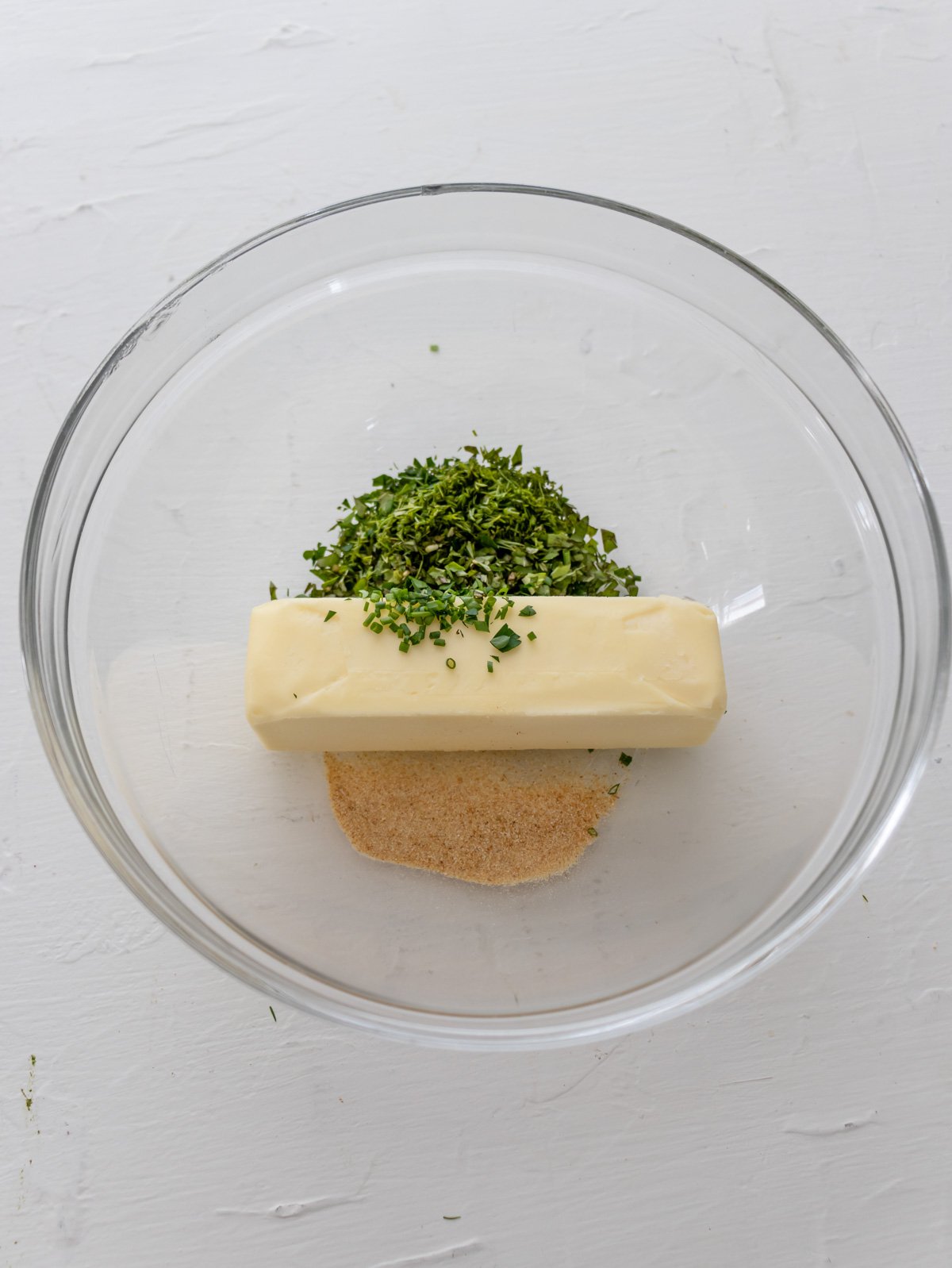 butter, garlic powder, and fresh minced herbs in a glass bowl. 