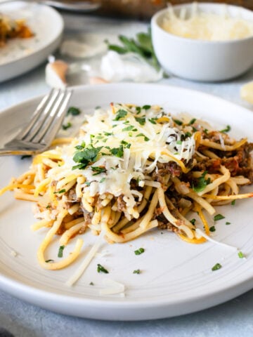 Baked spaghetti casserole on a white plate with a fork.