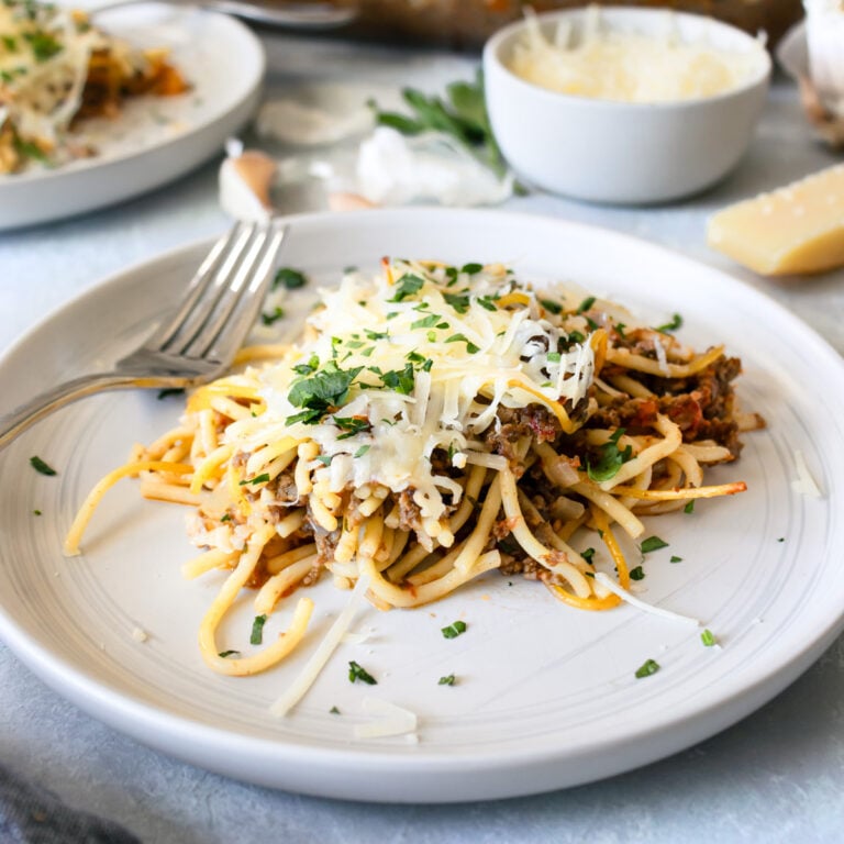 Baked spaghetti casserole on a white plate with a fork.
