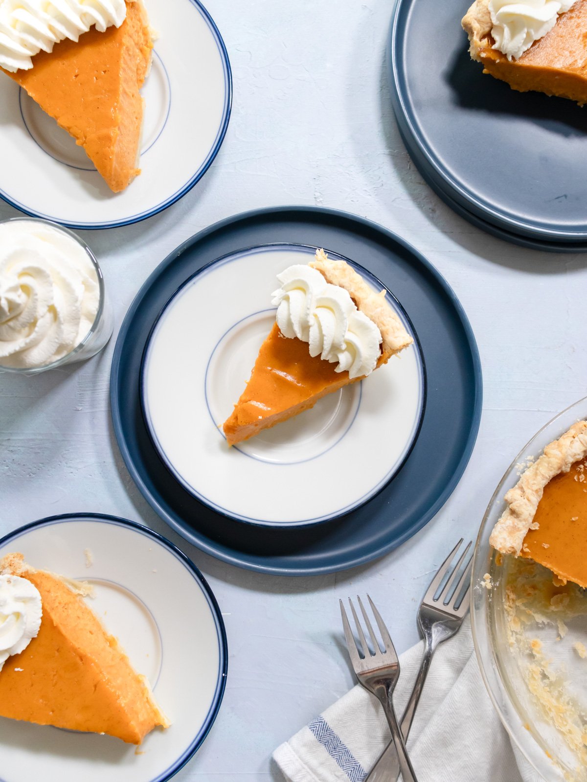 3 slices of sweet potato pie on blue plated with whipped cream. 