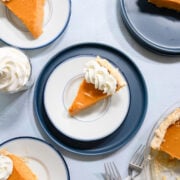 a slice of sweet potato pie on a small blue plate with whipped cream.