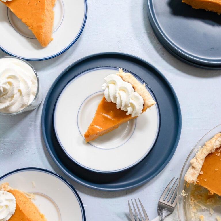 a slice of sweet potato pie on a small blue plate with whipped cream.