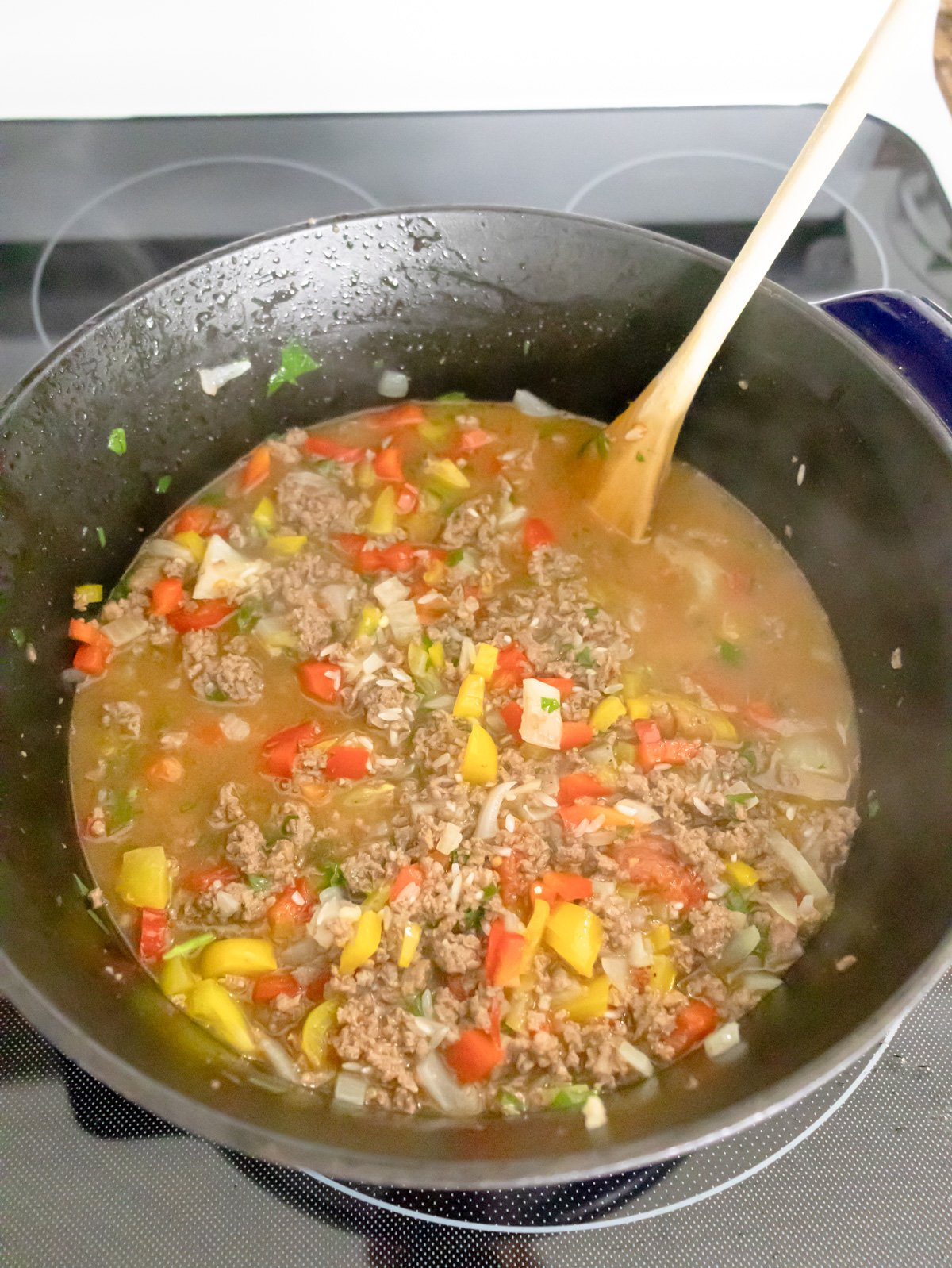 The filling for ground beef and rice casserole cooking in a pot on the stove.