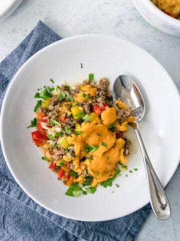 Ground beef and rice casserole dished out onto a bowl with a spoon next to it.
