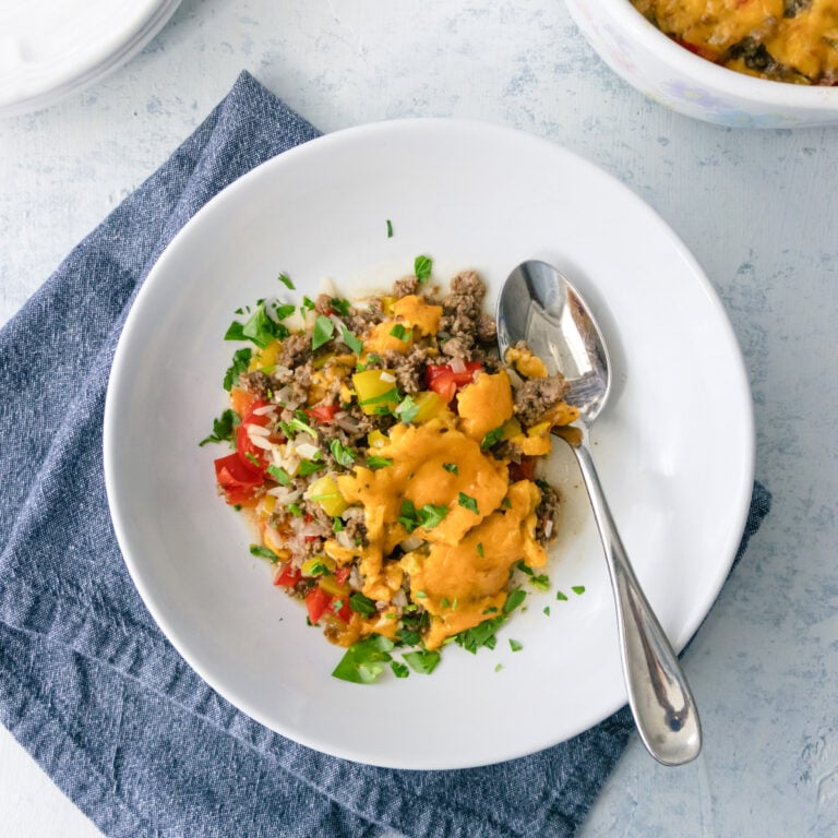Ground beef and rice casserole dished out onto a bowl with a spoon next to it.
