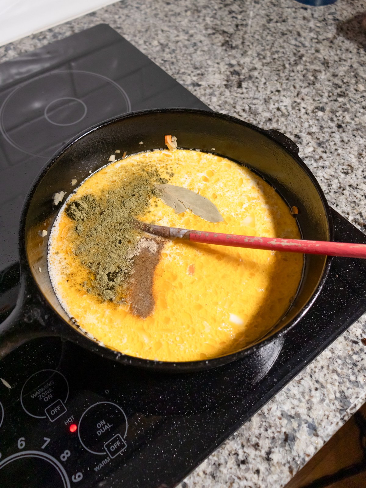 seasoning chicken stock and cream with some spices cooking on the stove.