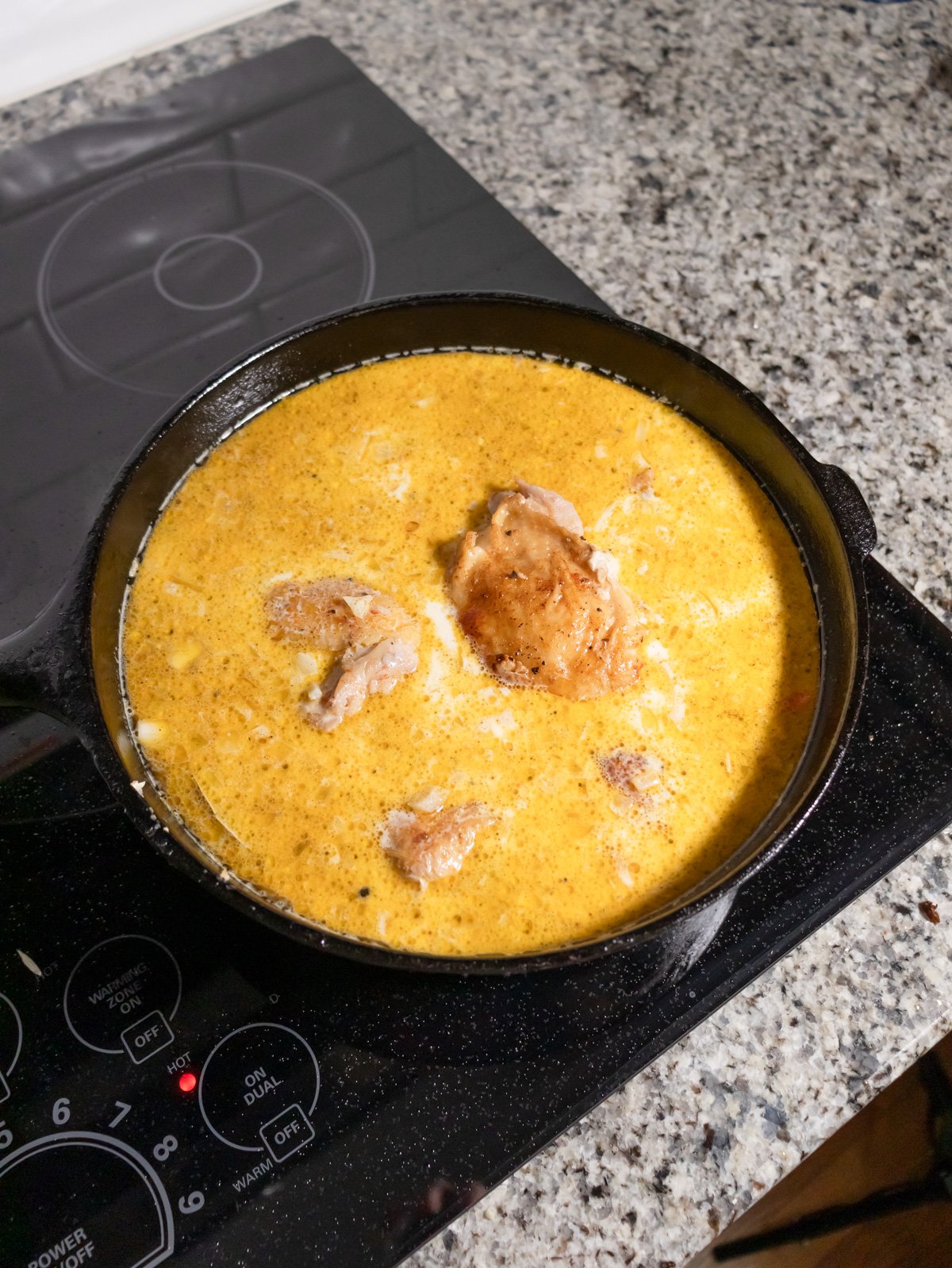 cooking chicken thighs and rice on the stove with cream and chicken stock.