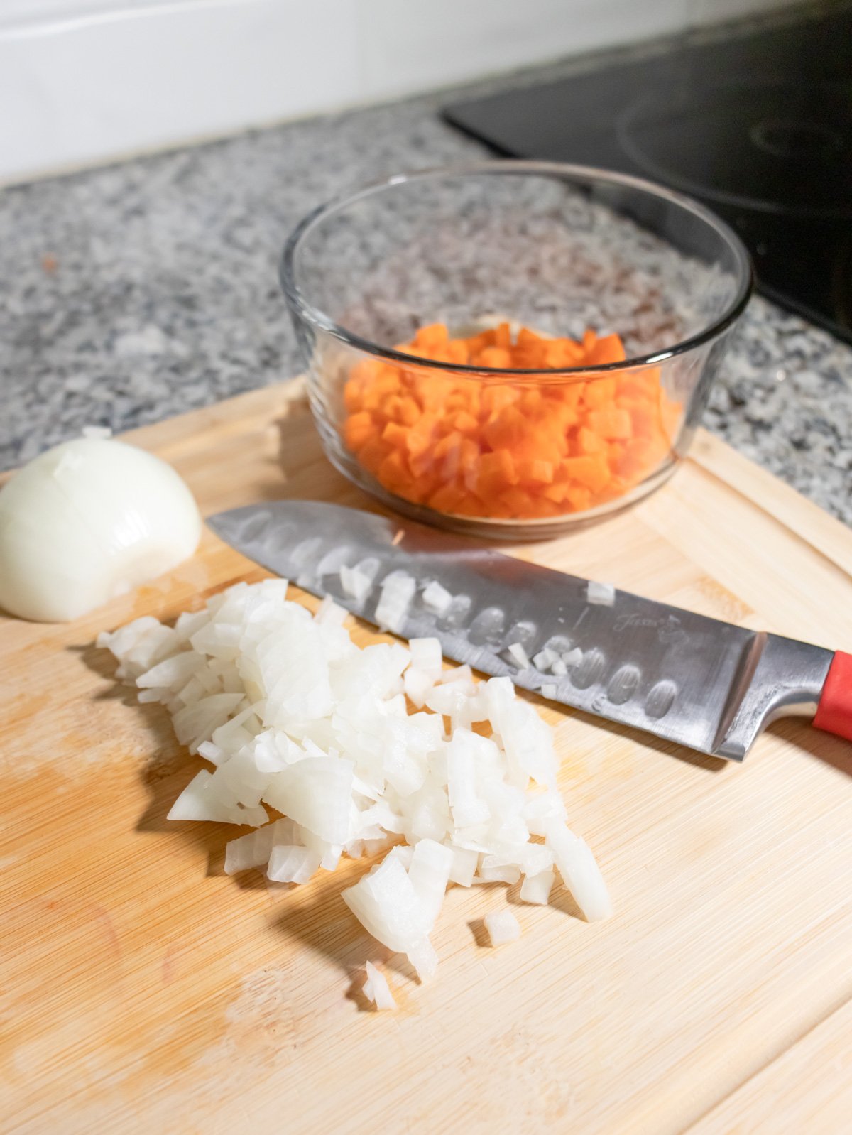 Chopping onions and carrots on a cutting board.