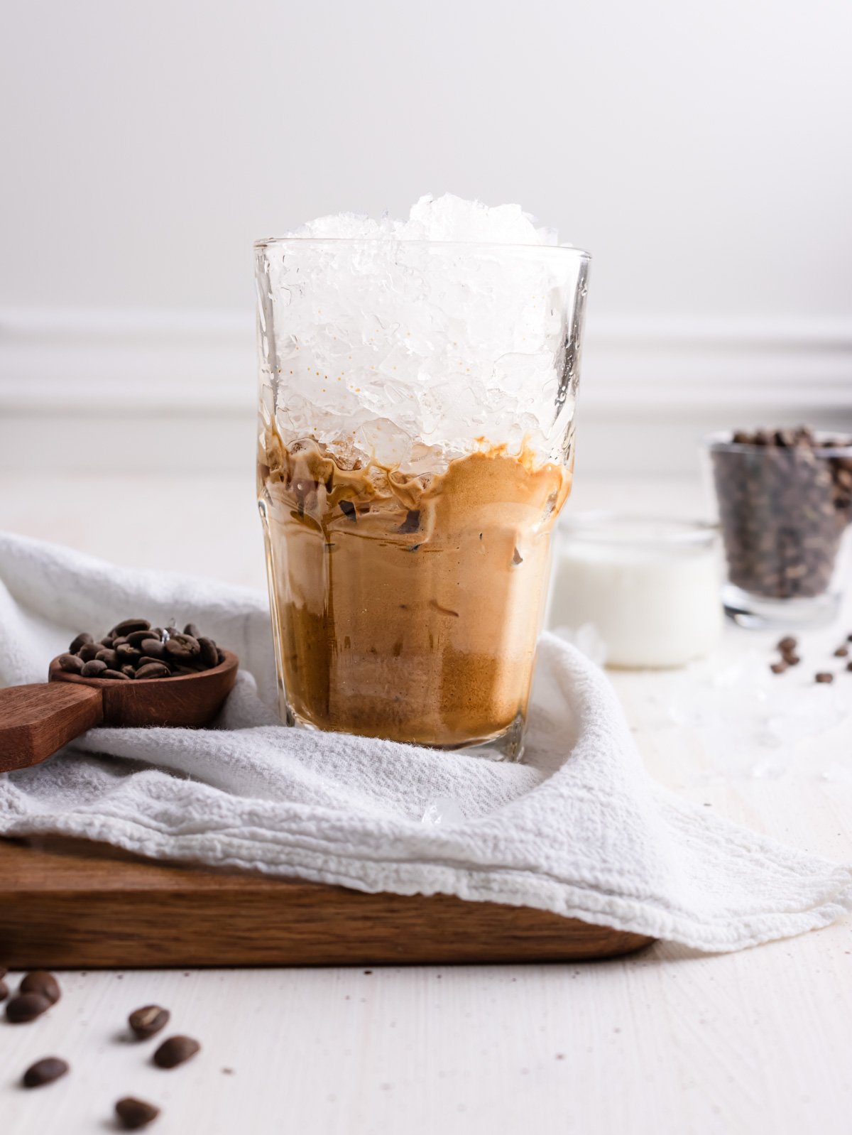 Adding ice to a coffee drinking in a clear glass.