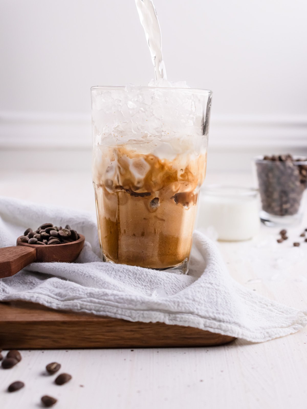 Adding water to iced coffee.