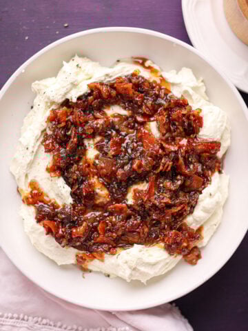 whipped feta with bacon jam in a white bowl.