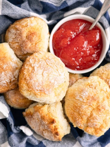 mashed potato biscuits in a basket with jelly next to them.