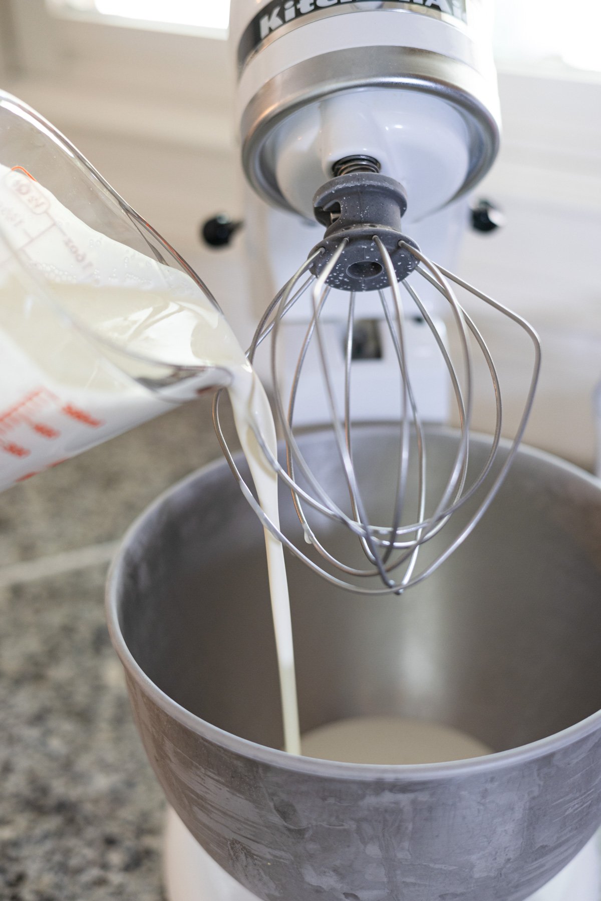 pouring cream in a stand mixer bowl.