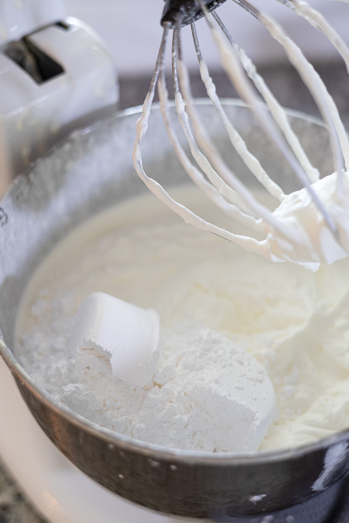 putting powdered sugar into a stand mixer making whipped cream. 
