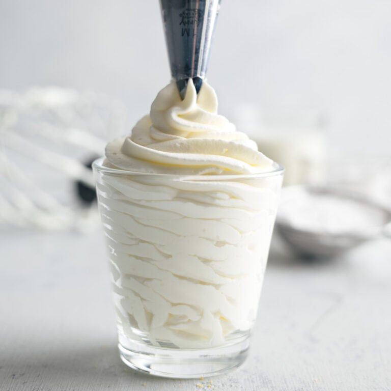 pipping homemade whipped cream into a clear cup with a piping bag nd tip.