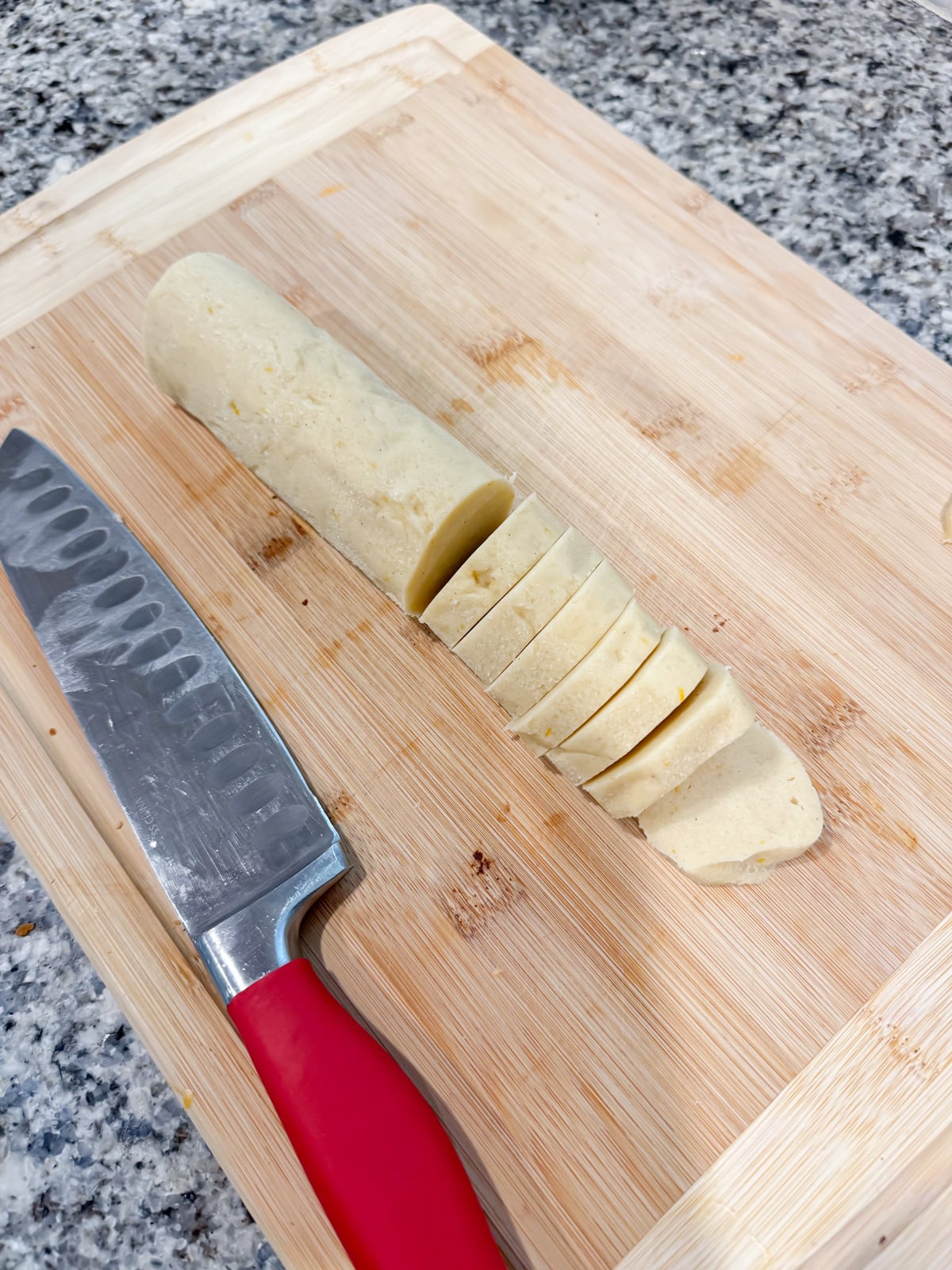slicing cookie dough on a cutting board.
