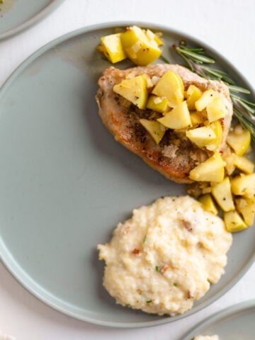 Apple cider glazed pork chops on a plate with cheese grits.