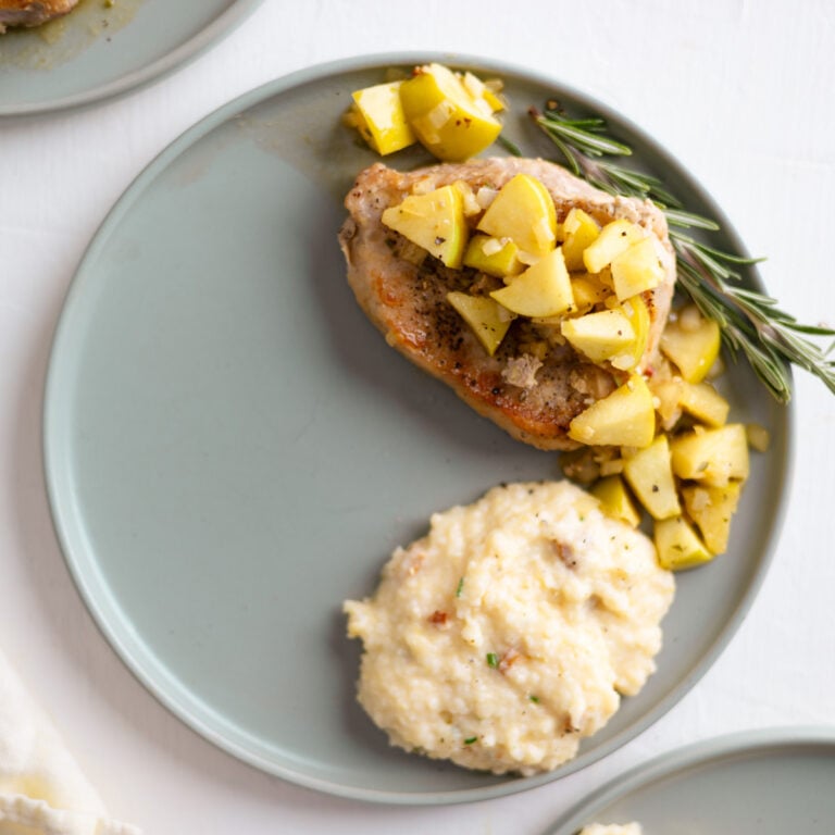 Apple cider glazed pork chops on a plate with cheese grits.