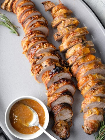 pork tenderloin sliced and payed out on a platter.