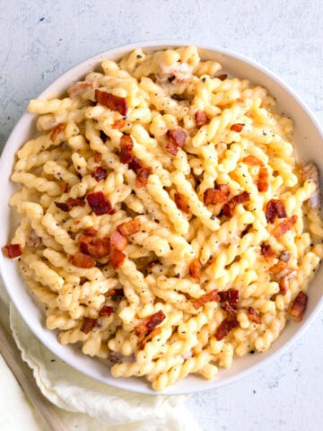 bacon Mac and cheese in a large serving bowl with a napkin next to it.