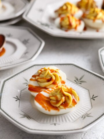 deviled eggs on a plate with BBQ sauce on top