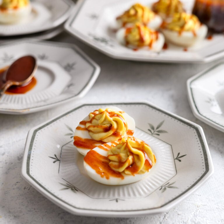 deviled eggs on a plate with BBQ sauce on top