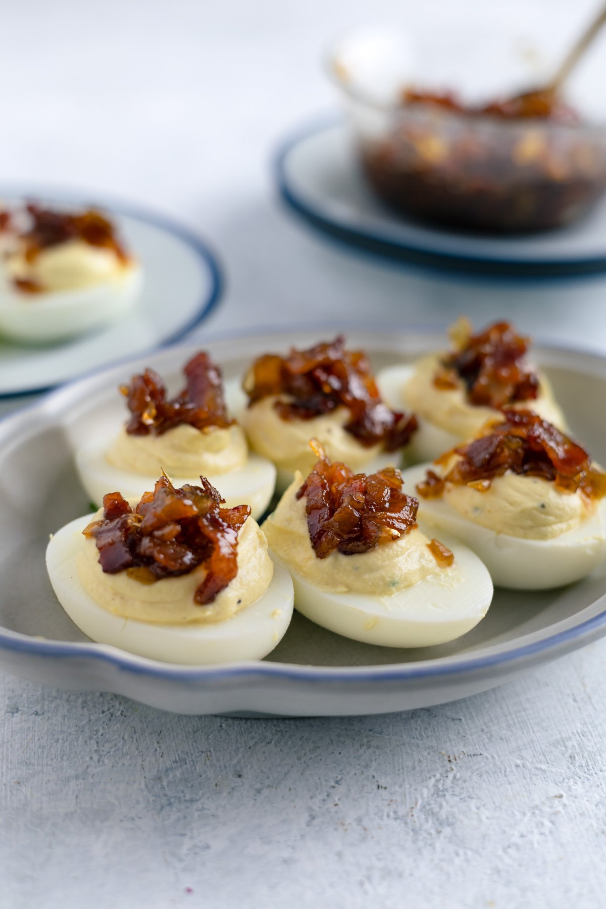 deviled eggs with bacon jam on top on a small platter