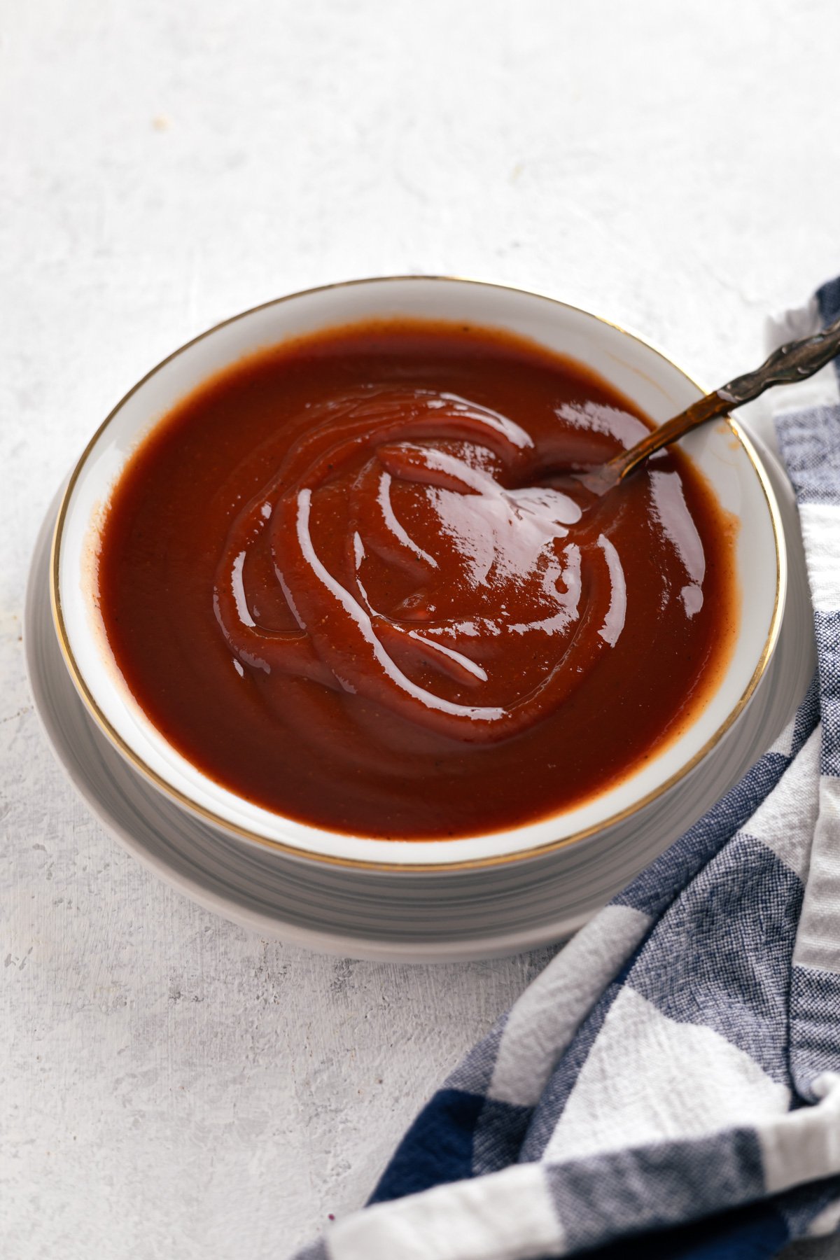 a shallow bowl of bbq sauce with a spoon in it.
