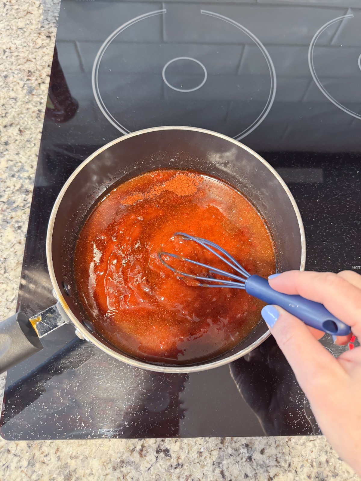 Stirring BBQ sauce in a pot on the stove.
