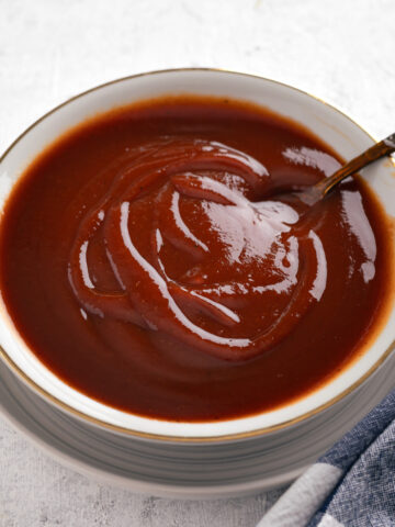 bourbon BBQ sauce in a shallow bowl with a spoon in it.