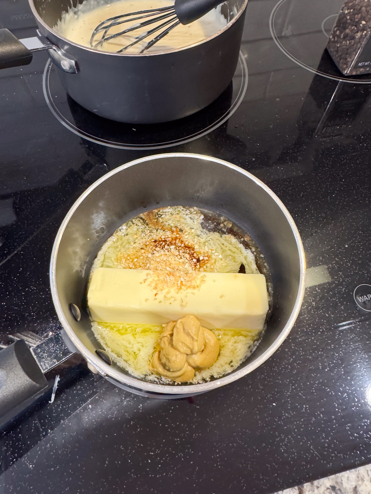 Butter, mustard and spices melting in a saucepan on the stove.
