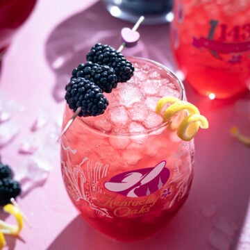 kentucky oak lily cocktail with blackberry and lemon peel garnish.