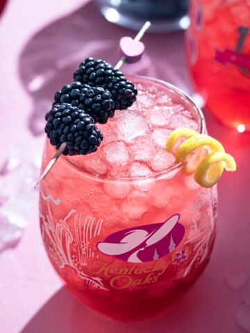 kentucky oak lily cocktail with blackberry and lemon peel garnish.