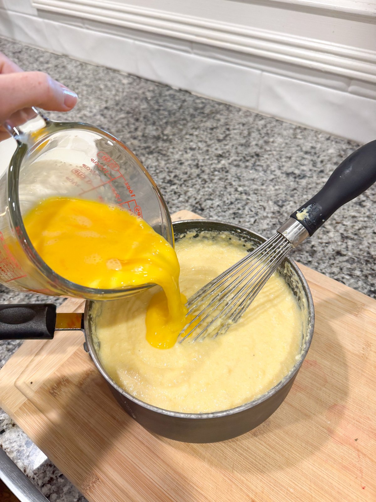 Adding eggs to spoon bread batter in a pot. 