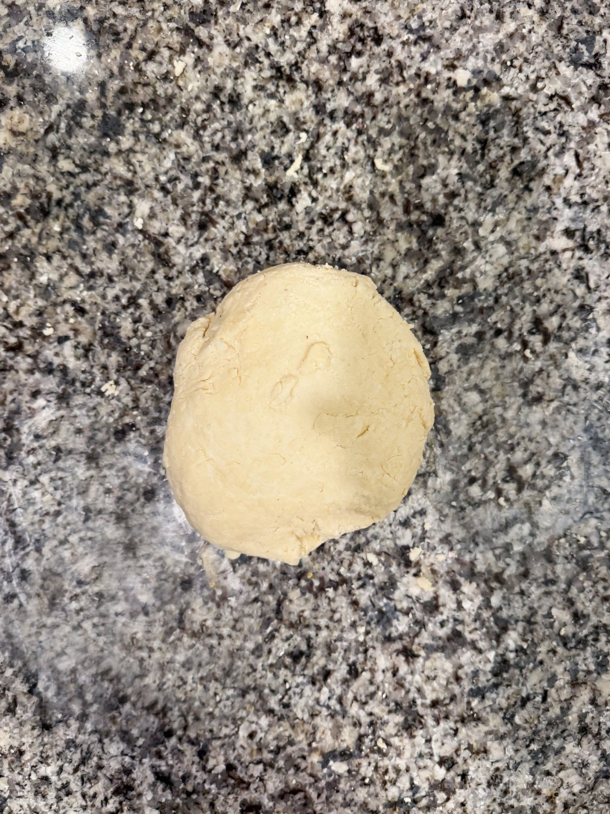 pie crust dough rolled into a ball on a floured kitchen counter. 