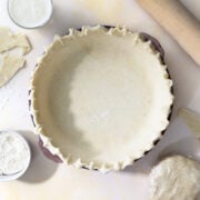 buttermilk pie crust in a pie shell with a rolling pin and flour next to it