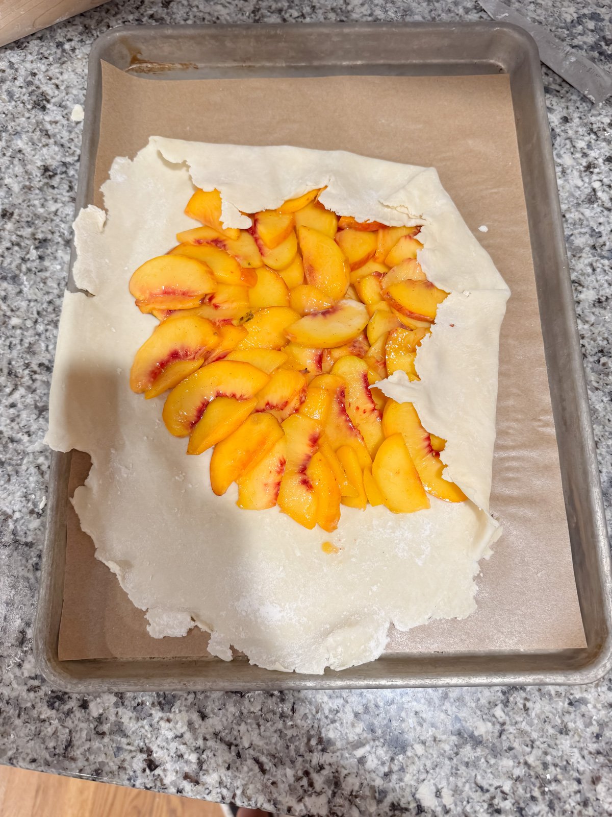 folding over the edges of a pie crust on sliced peaches.