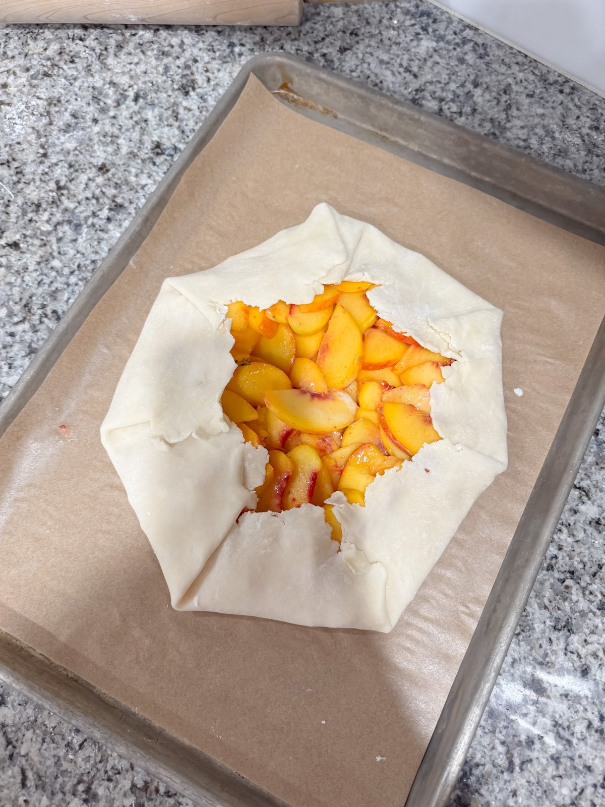peach galette on a baking sheet before going into the oven.