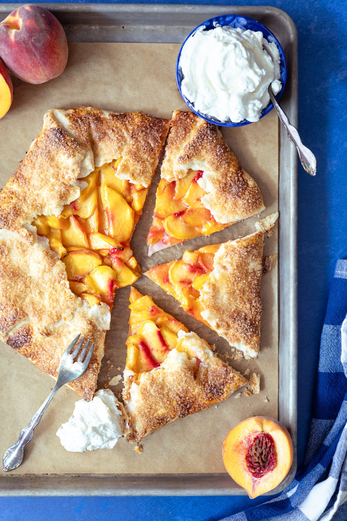 peach galette on a baking sheet cut until 3 pieces with a fork and whipping cream