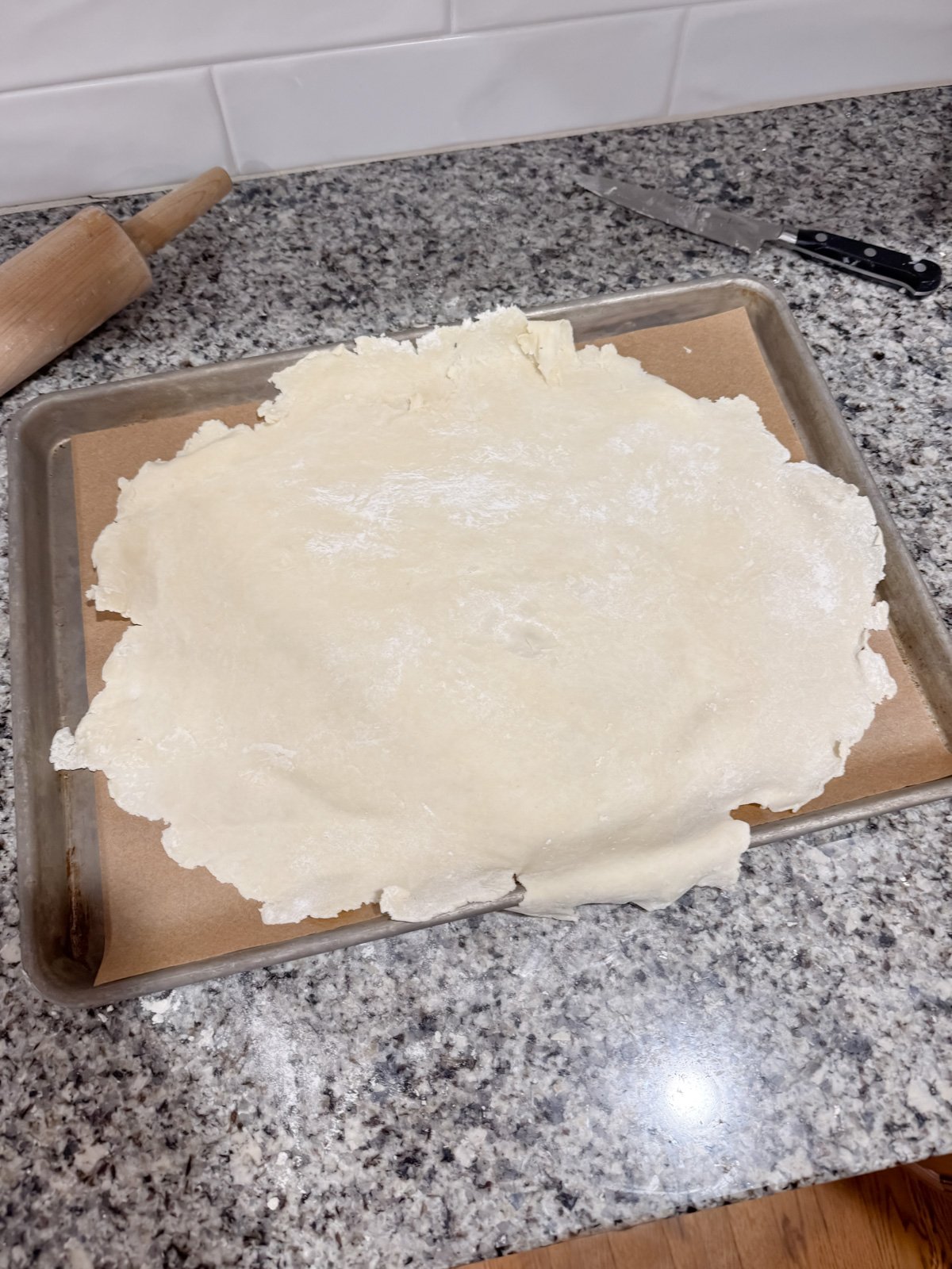 a pie crust rolled out on a baking sheet with parchment paper. 