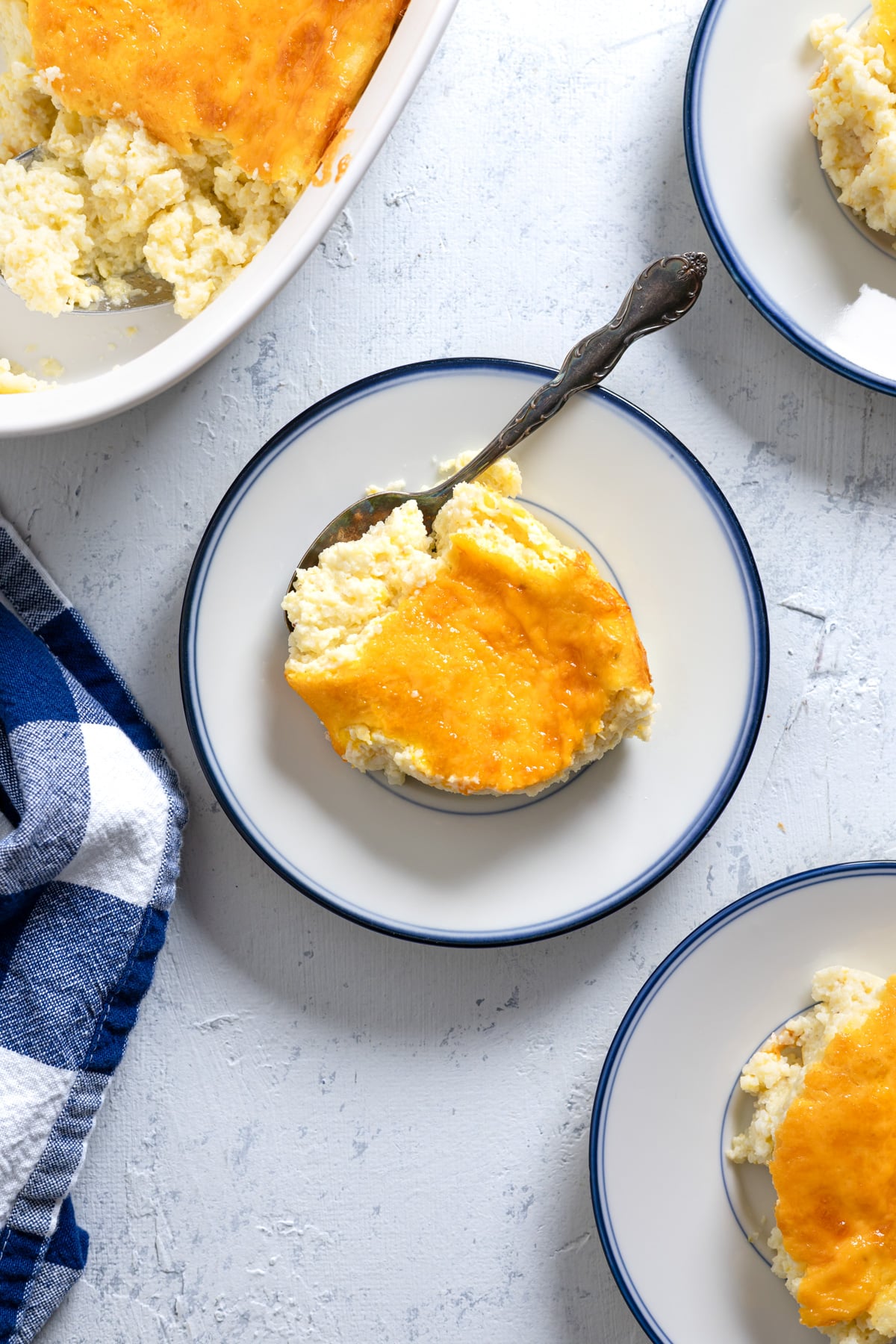 small plates and a baking dish of baked grits casserole.