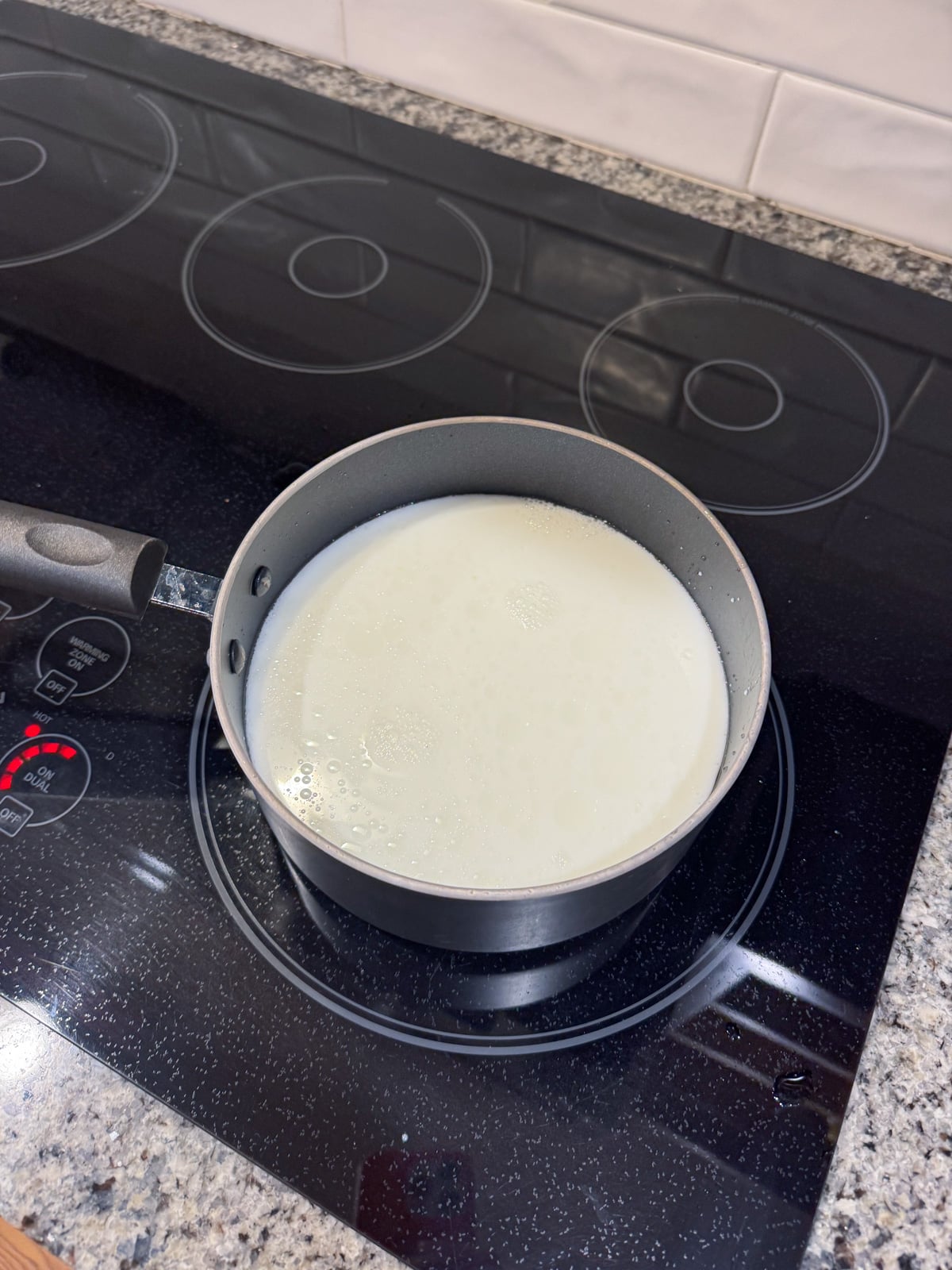 a pot of milk on the stove shimmering.