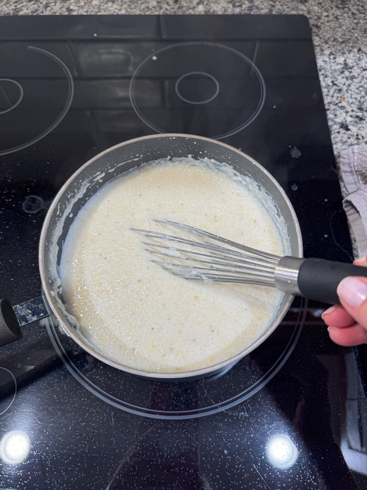 Whisking grits cooking in a pot on the stove.