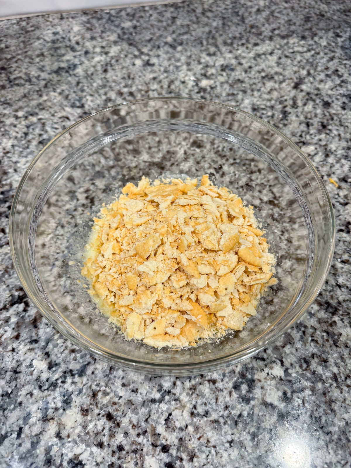 mixing together ritz crackers and butter in a bowl.