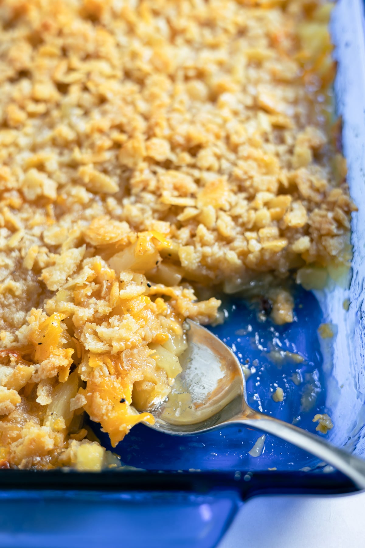 scooping out some pineapple casserole with a serving spoon