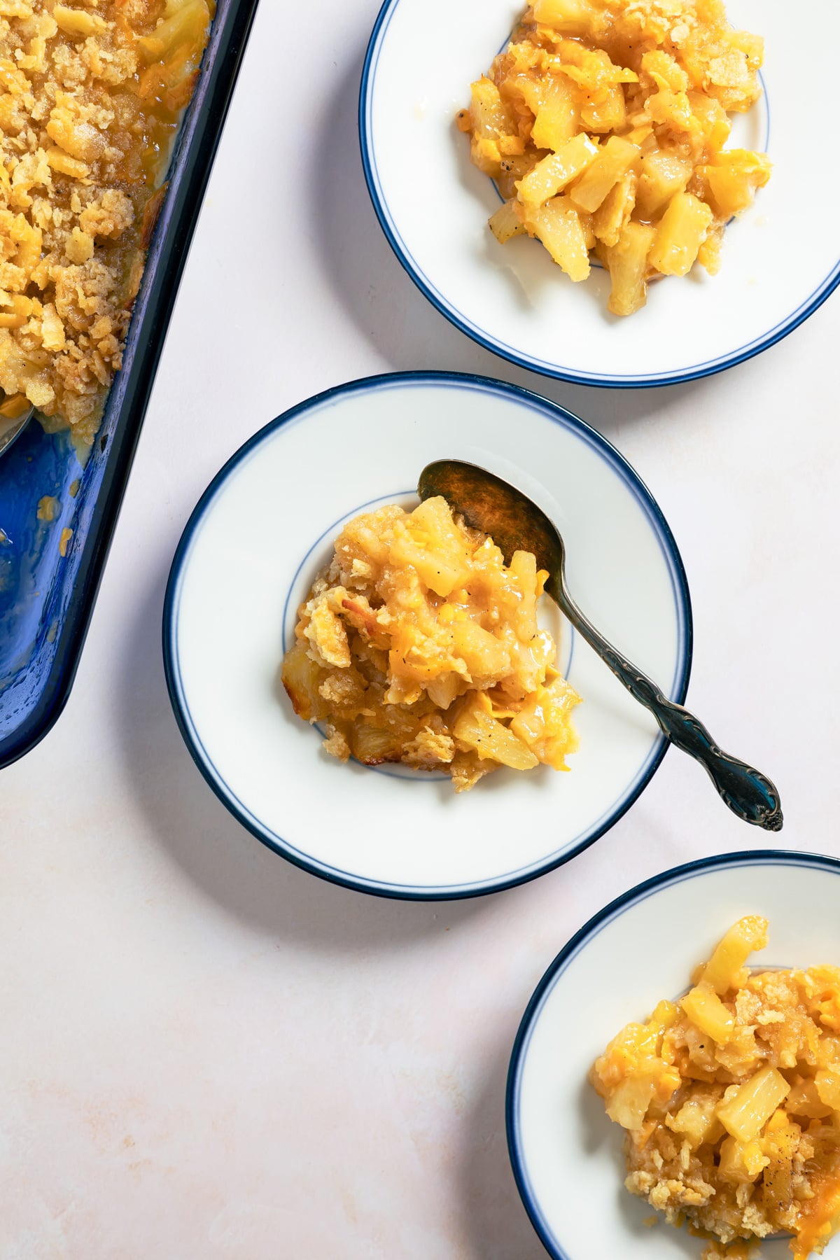3 small plates of pineapple and cheese casserole with a spoon next to one. 