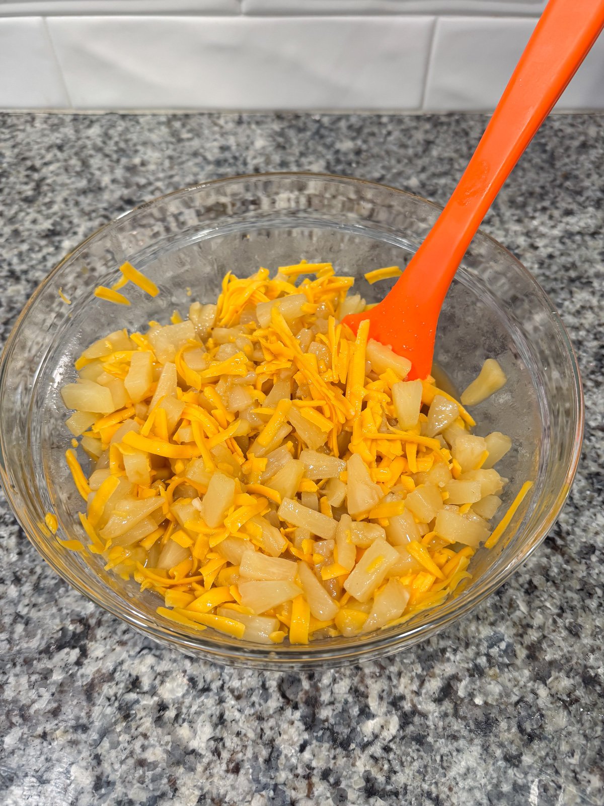 Stirring the filling of pineapple and cheese casserole in a large bowl.