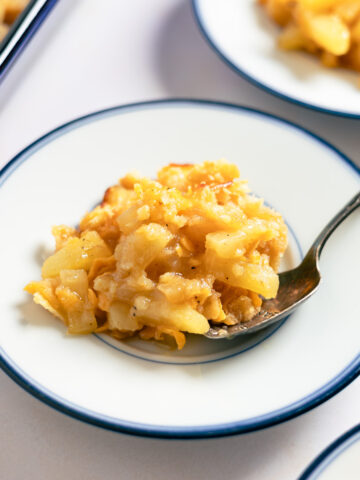 a scoop of pineapple cheese casserole on a small blue plate